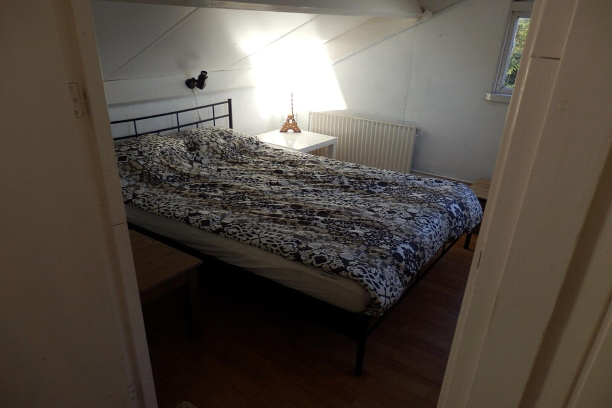 Une chambre à coucher avec un lit, une table de chevet, une lampe et un radiateur.