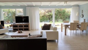 Ein Wohnzimmer mit Fernseher, einer Couch, einem Couchtisch und einem Essbereich mit Stühlen und Tisch.