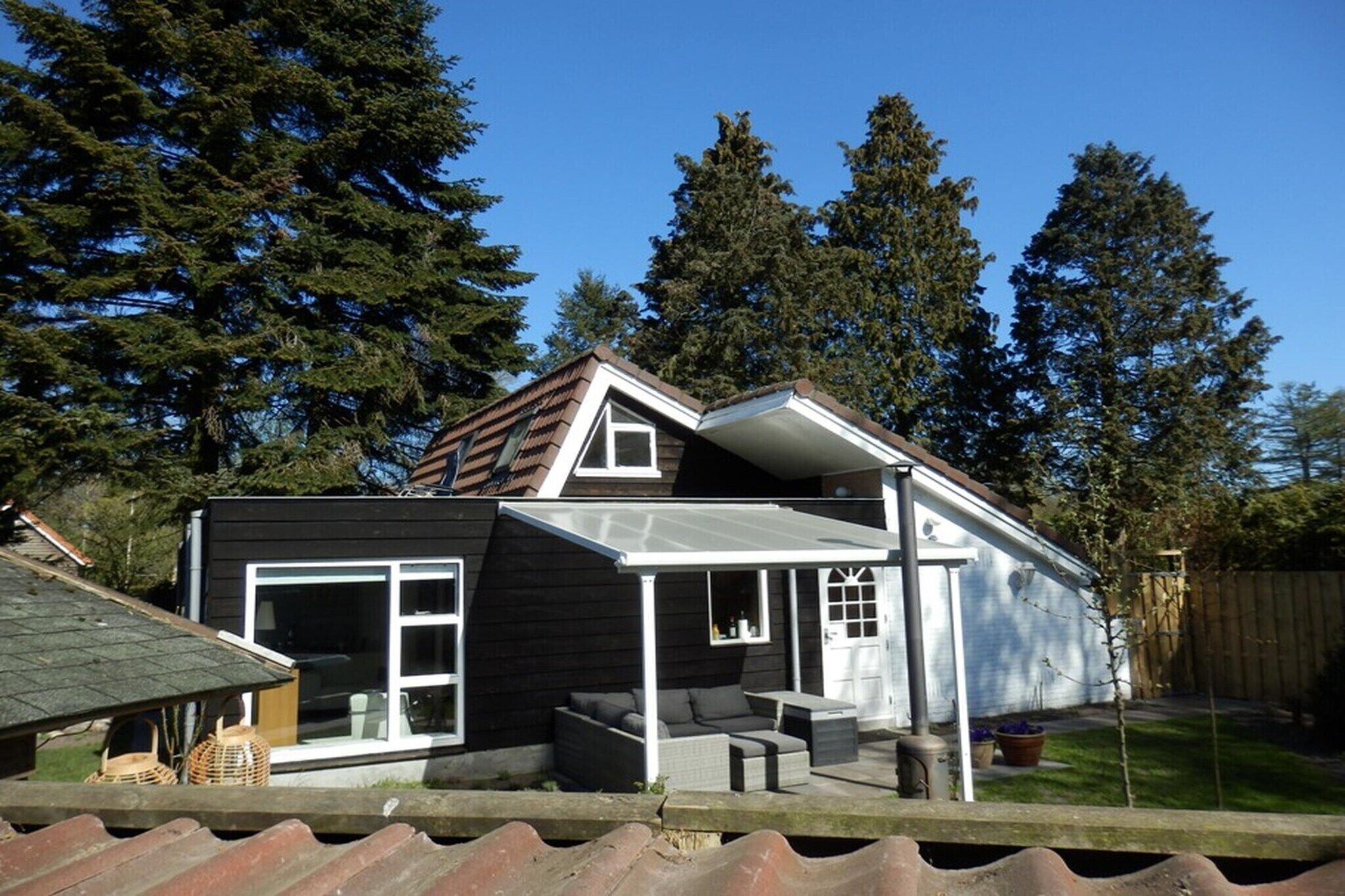 A modern house with a large glass door, a covered patio, and a sloped roof.