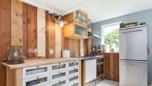 Eine Küche mit Holzwänden, einem Edelstahlkühlschrank und einem eingebauten Backofen.