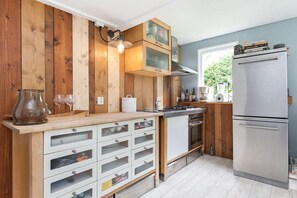 A kitchen with wooden walls, a stainless steel refrigerator, and a built-in oven. - Family Villa with Jacuzzi & Large Garden (Balkbrug)