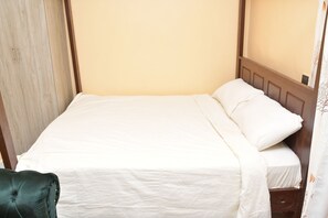 A single bed with a wooden headboard and a plain white bedspread. - Maria villa studio Beautiful 1-bnb in enjoyable Voi for a relaxing stay (Voi)