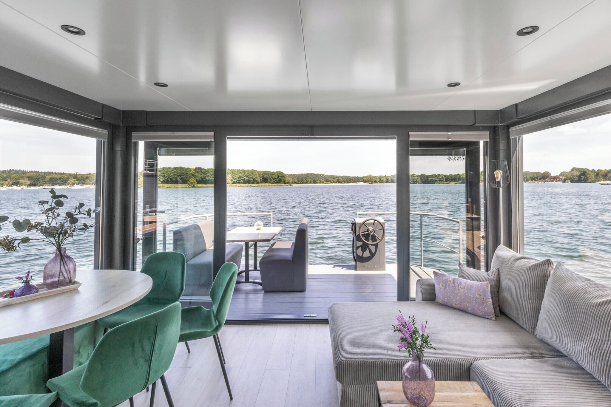 A modern interior with a dining area, seating, and a view of the water.