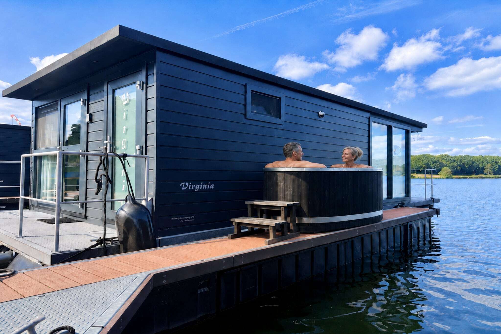Ein schwimmendes Haus mit Whirlpool und einer anlegbaren Plattform, die ins Wasser ragt.