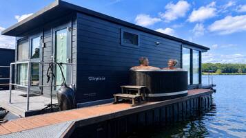 Ein schwimmendes Haus mit Whirlpool und einer anlegbaren Plattform, die ins Wasser ragt.