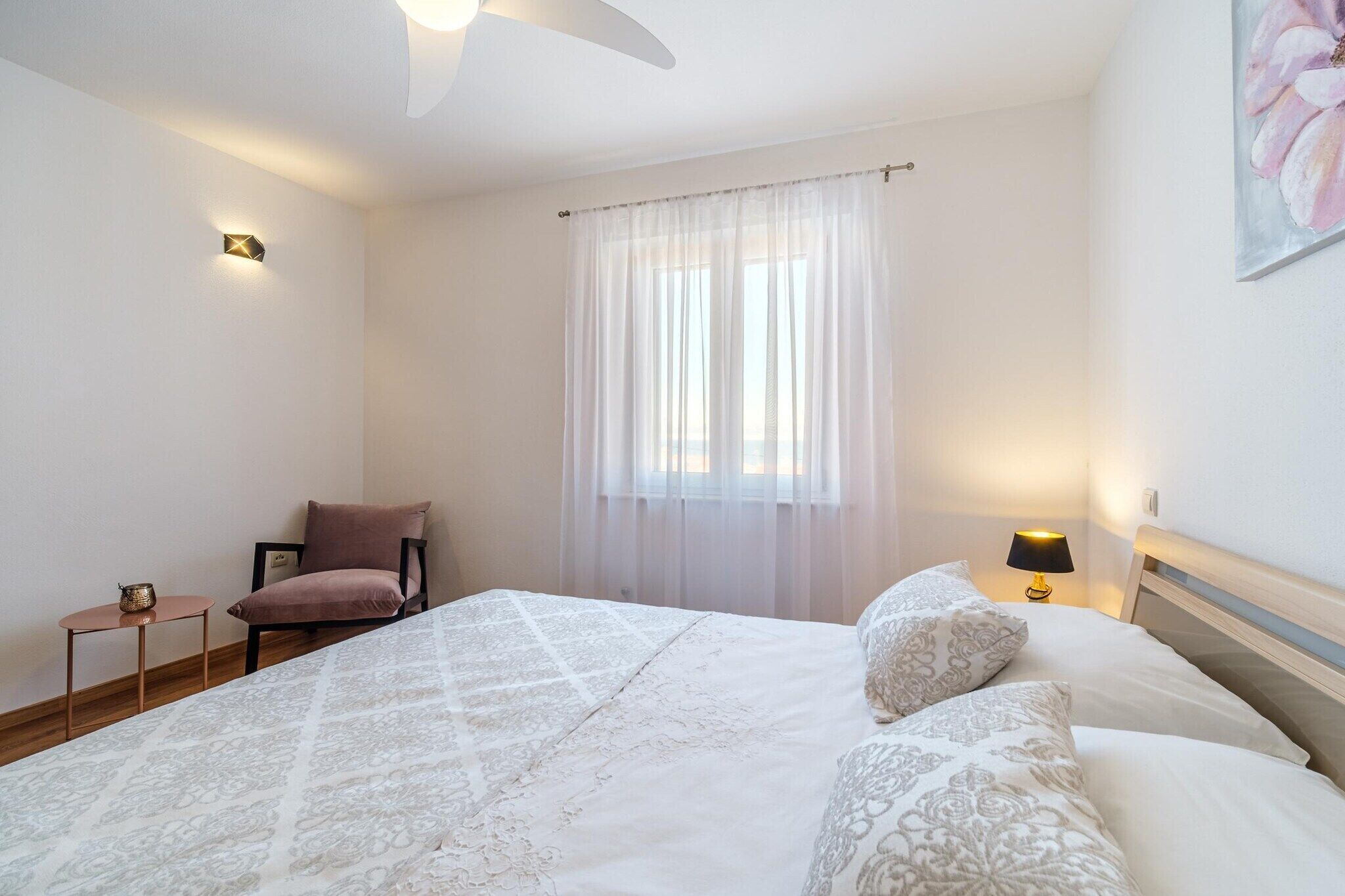 A bedroom with a bed, a chair, a small table, and a lamp.