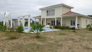 Une maison à deux étages dotée d’une piscine, d’un espace salon extérieur et d’un patio couvert.