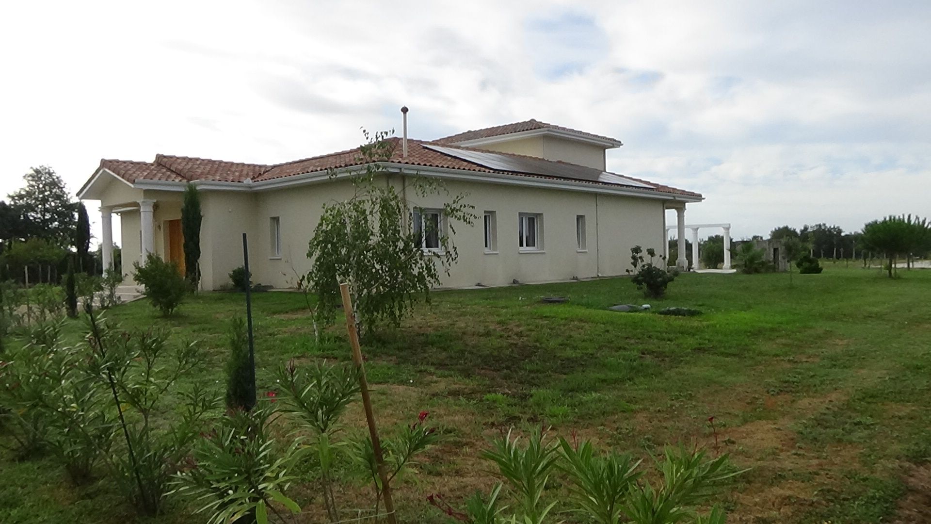 A single-story house with a tiled roof, a front porch, and a well-maintained lawn.