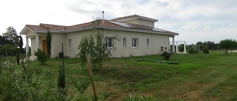A single-story house with a tiled roof, a front porch, and a well-maintained lawn.
