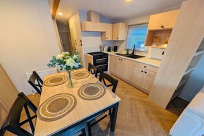 A compact kitchen with a dining area, featuring a central island, built-in cabinets, and a stove. - Mobile Home with Shared Pool for 6 Guests (Zonhoven)