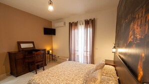 A hotel room with a bed, a desk, a chair, a television, and a window with curtains.