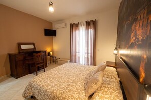A hotel room with a bed, a desk, a chair, a television, and a window with curtains.