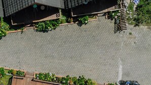 Vista aérea de un patio con zona pavimentada, terraza de madera y fila de motocicletas estacionadas.