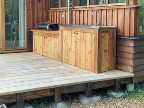 Terraza de madera con barra integrada, pileta y parrilla.