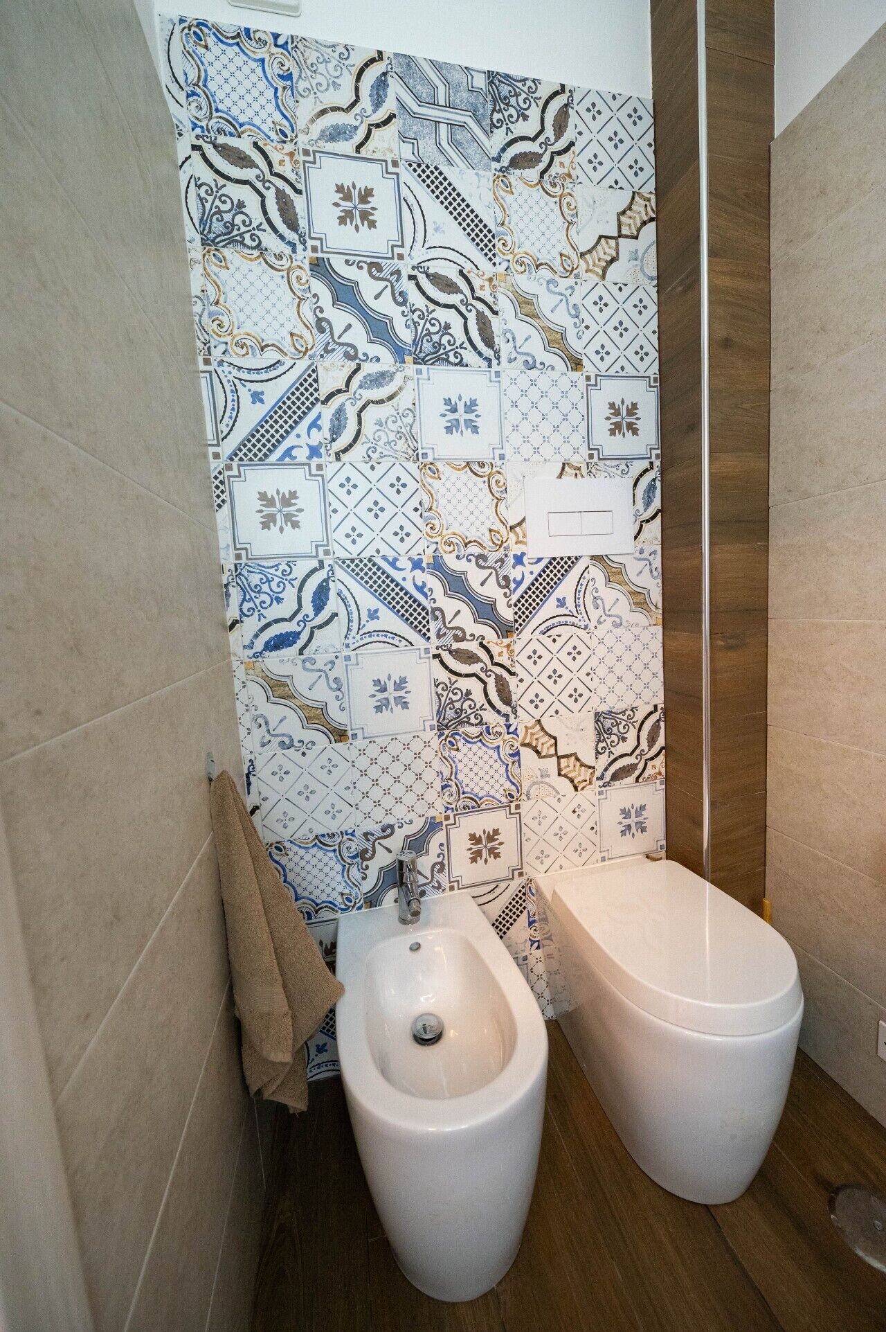 Une salle de bain équipée d’un bidet, d’une serviette et d’un mur décoré d’un motif.