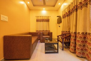 A living room with a brown sofa, a glass coffee table, and a wooden chair.