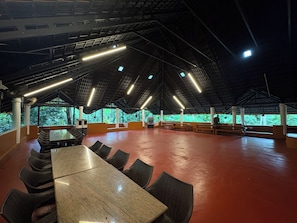 An indoor space with a high ceiling, multiple seating areas, and a view of greenery outside. - River Country (Nedumangad)