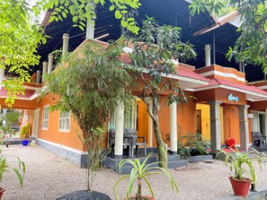 A building with a covered outdoor area, potted plants, and a sign that reads 'Cocacola'.