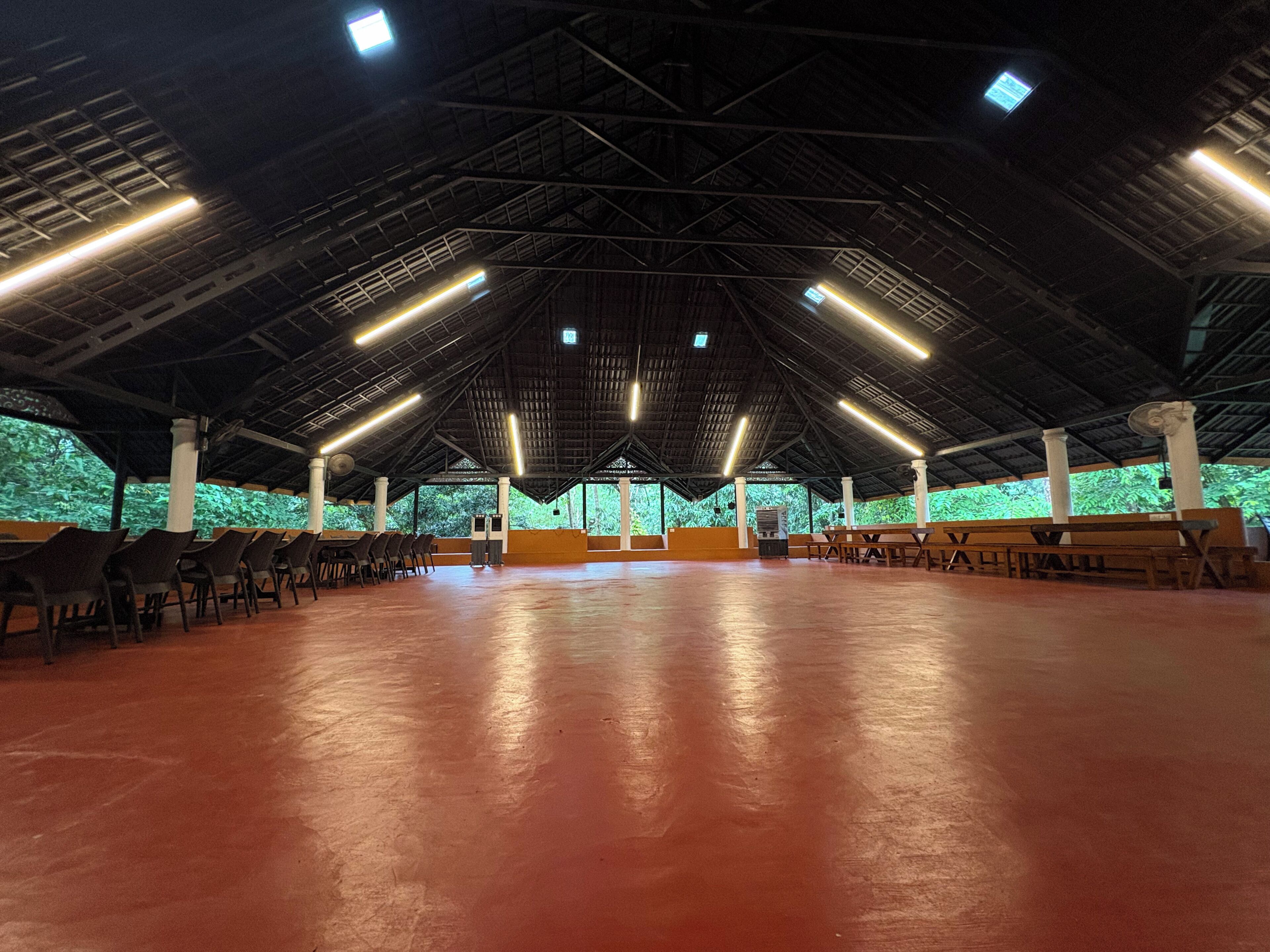 Um espaço interno com teto alto, fileiras de cadeiras e uma área central com um banco.