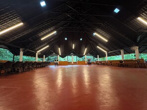 An indoor space with a high ceiling, rows of chairs, and a central area with a bench.