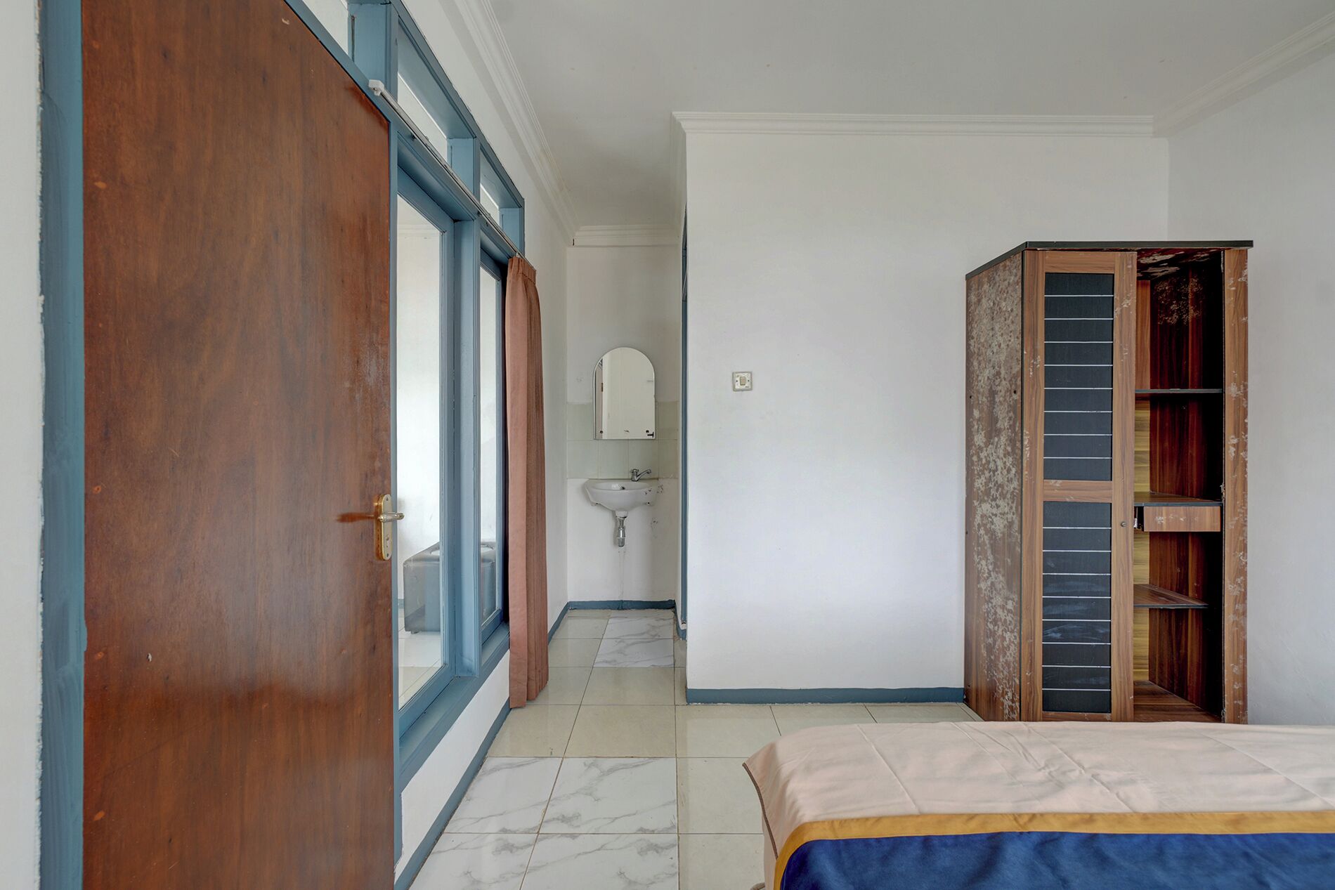 Un dormitorio con cama, un armario de madera, un baño con lavamanos y un espejo.