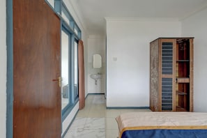 Un dormitorio con cama, un armario de madera, un baño con lavamanos y un espejo.