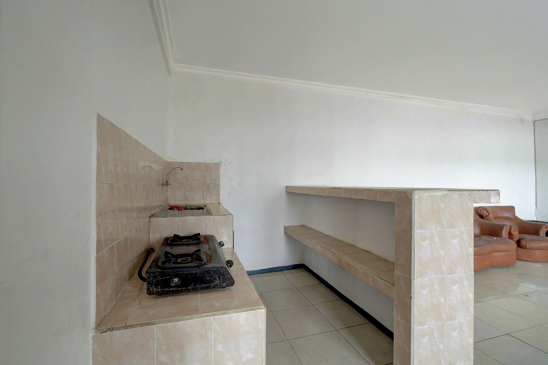 Una habitación con piso de baldosas, un banco empotrado con repisa y una estufa a gas.