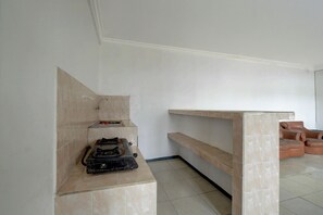 Una habitación con piso de baldosas, un banco empotrado con repisa y una estufa a gas.