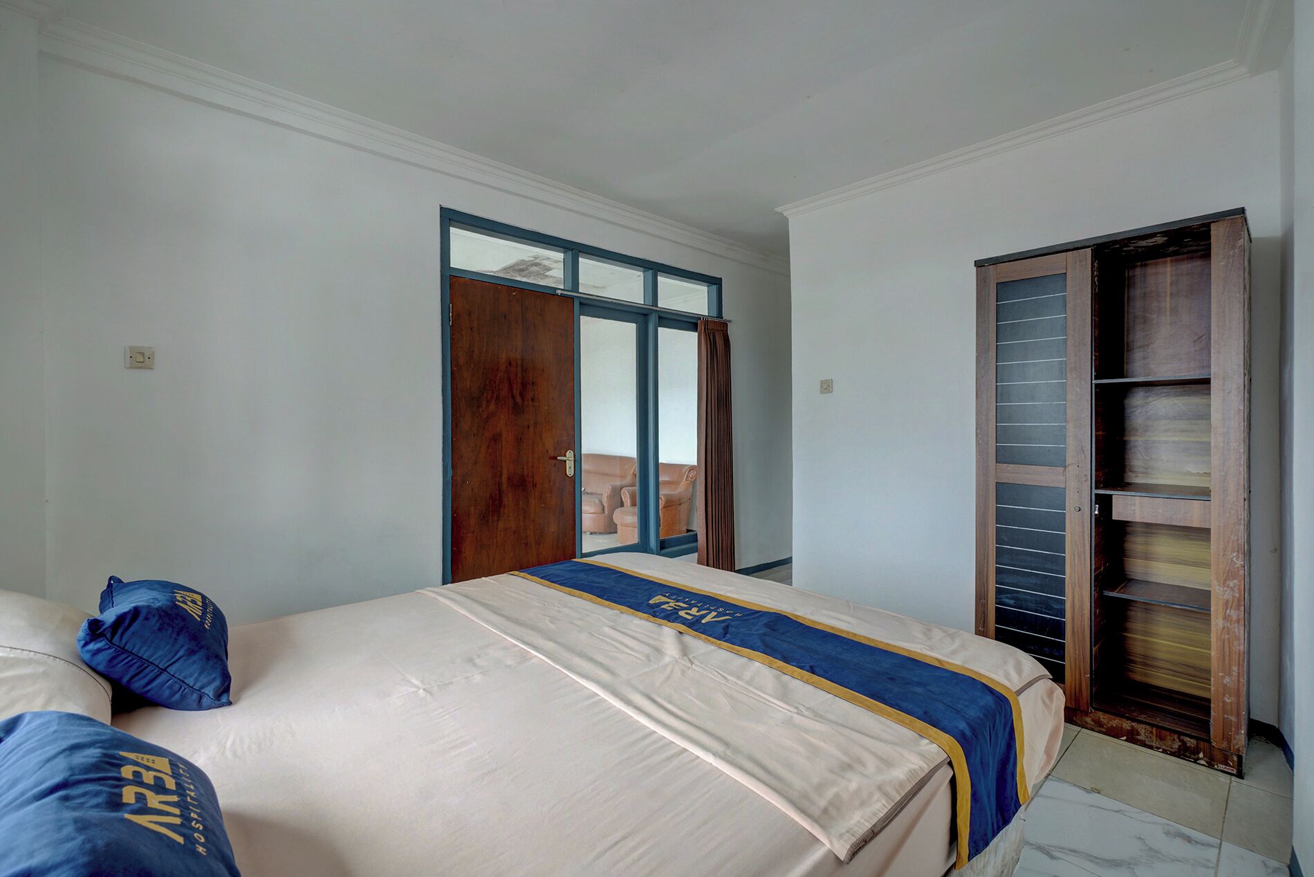 Una habitación de hotel con cama, armario y ventana.