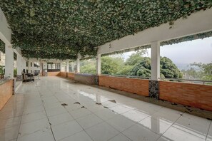 Un espacio interior amplio con suelo de baldosas, un largo banco a lo largo de la pared y vistas a zonas verdes.