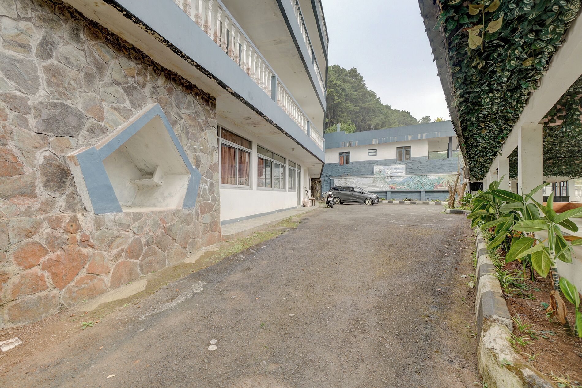 A building with a stone facade, a covered outdoor area, and a parked car.