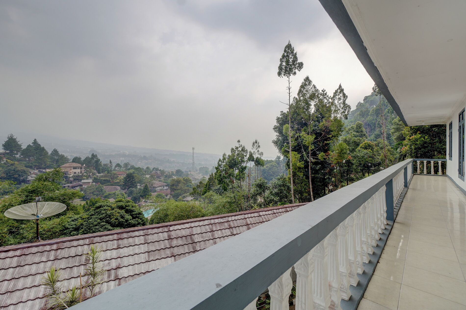 Un balcón con vistas a una zona residencial y árboles.