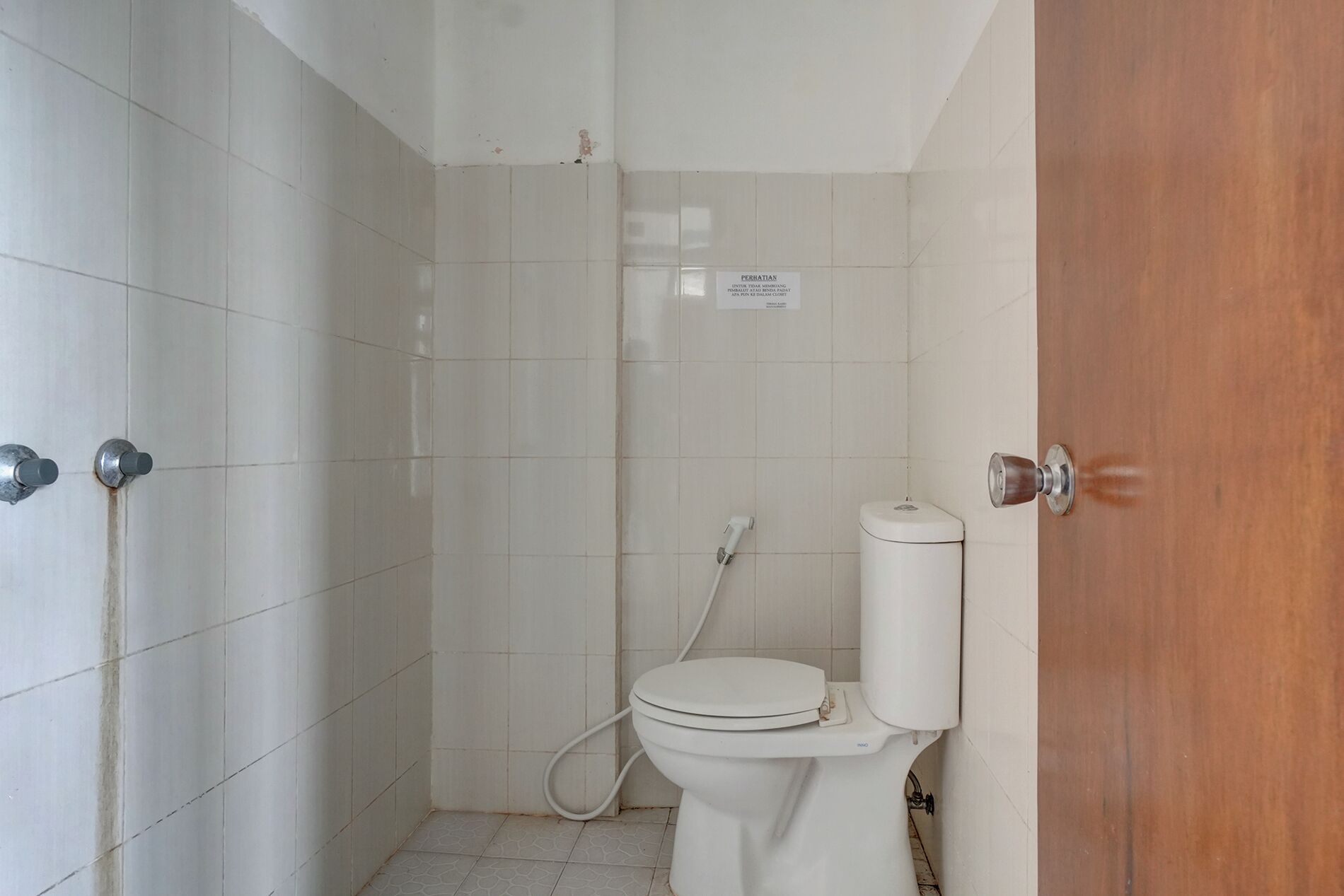 Un baño pequeño y cerrado con inodoro, ducha y puerta.