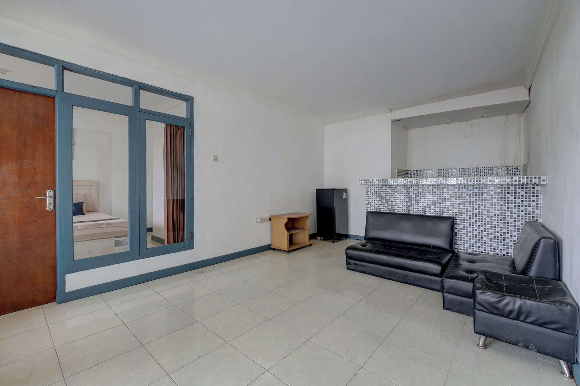 Una sala de estar con un sofá, un televisor y una puerta corredera que da a un dormitorio.
