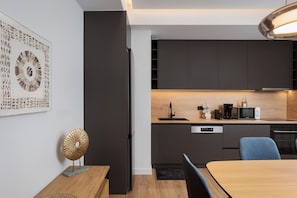 A modern kitchen with dark cabinetry, a built-in microwave, and a coffee maker. - Acropolis Executive Residence  | Chatzichristou Str.16.Athens 11742, Bill & John Apartments & Villas (Athens)
