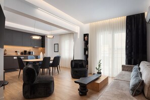 A modern living room with a dining area, a kitchen, and a large window with sheer curtains. - Acropolis Executive Residence  | Chatzichristou Str.16.Athens 11742, Bill & John Apartments & Villas (Athens)