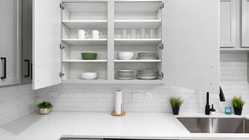 Una cocina moderna con armarios blancos, un lavamanos de acero inoxidable y un escurreplatos.