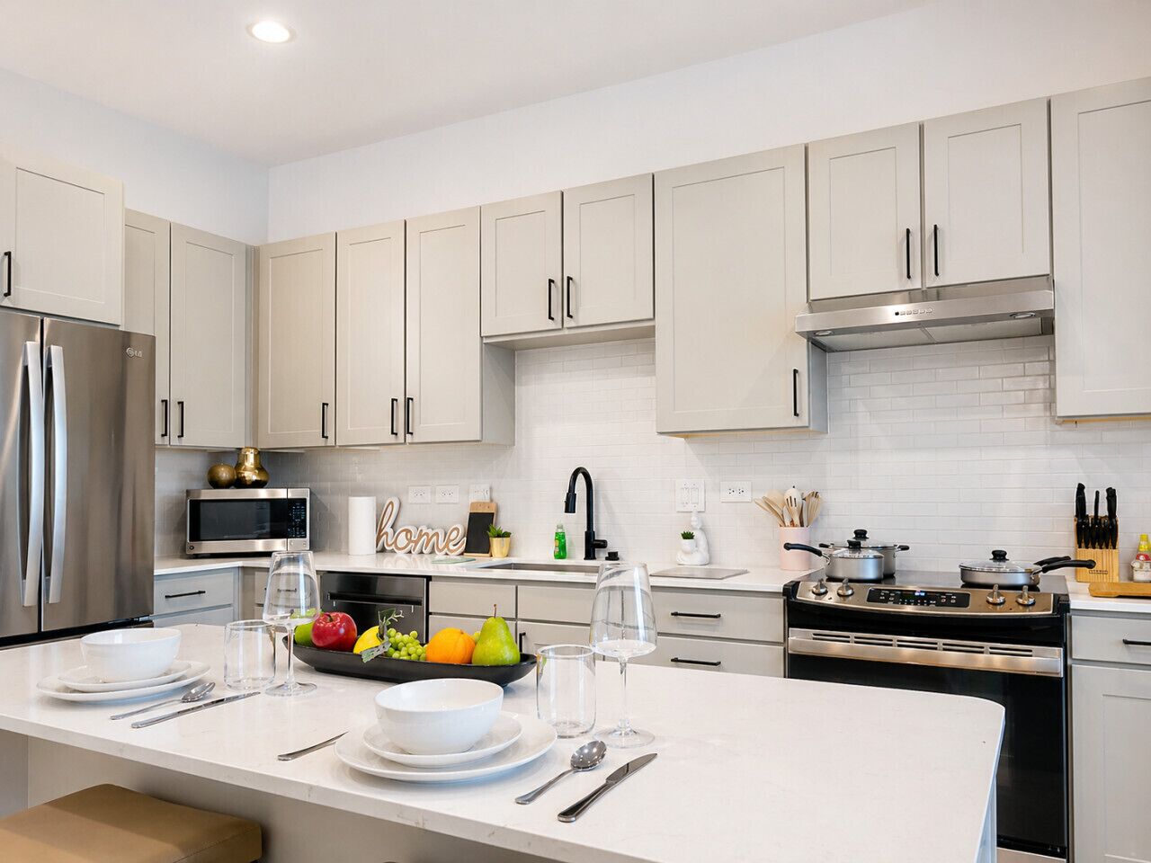 Una cocina moderna con electrodomésticos de acero inoxidable, armarios blancos y una isla central con zona de comedor.