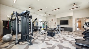 A gym with various exercise equipment, a patterned floor, and a television on the wall.