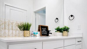 A white bathroom with a mirror, a sink, a towel ring, and a sign that reads 'wash your hands (no, seriously)'.