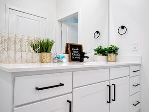 A white bathroom with a mirror, a sink, a towel ring, and a sign that reads 'wash your hands (no, seriously)'.