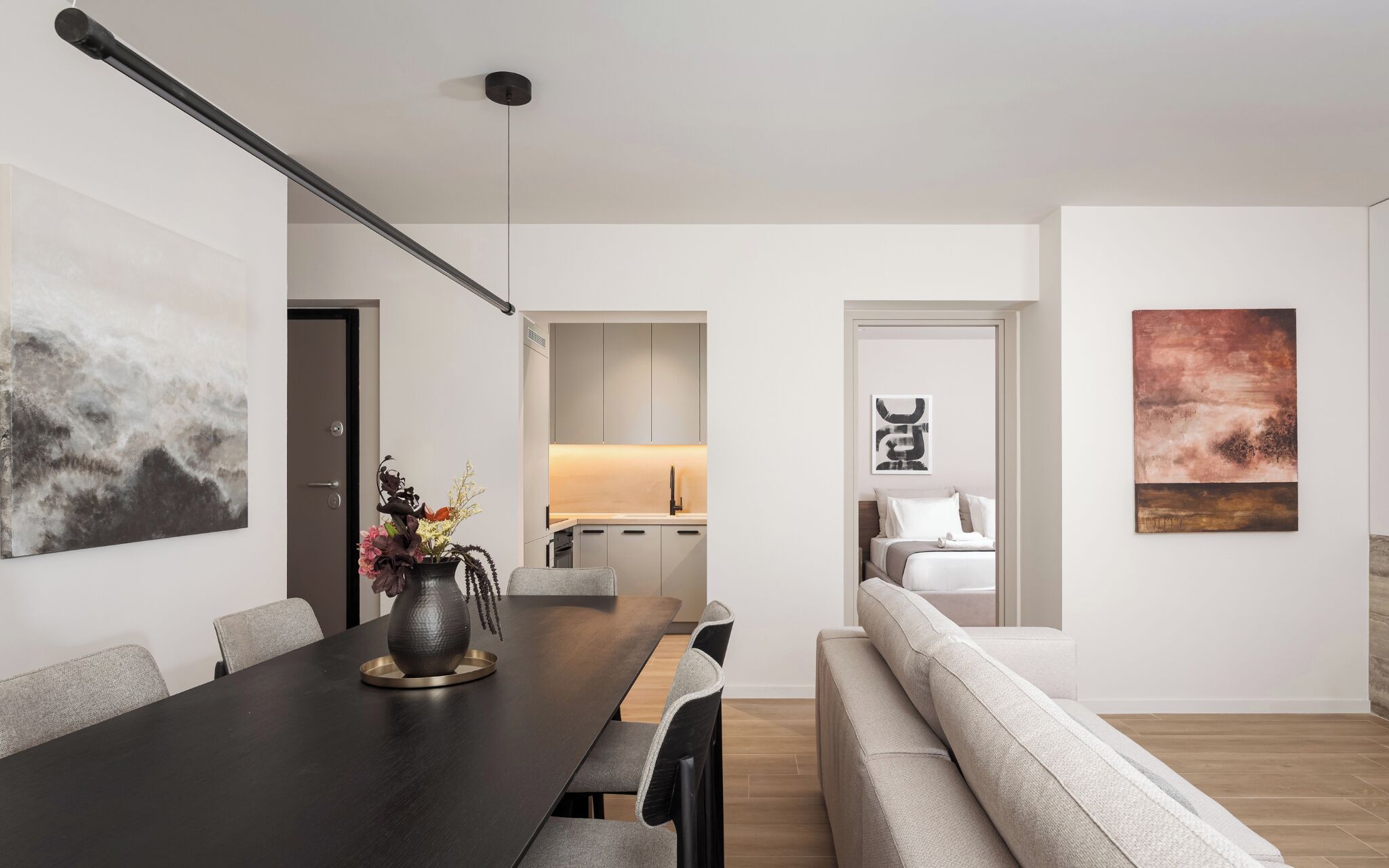 A modern interior with a dining area, a sofa, and artwork on the walls.