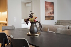 Ein Esstisch mit Blumen in einer Vase und einer Kerze, umgeben von Stühlen.