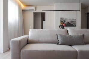 A modern living room with a sofa, a vase with flowers, and a painting on the wall. - Glyfada Prime Signature Residence, Glyfada Prime Living (Glyfada)