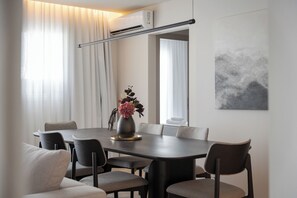 A modern dining area with a dark wooden table, grey upholstered chairs, and a vase with flowers. - Glyfada Prime Elegant Residence, Glyfada Prime Living (Glyfada)