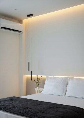 A modern bedroom with a bed, a bedside table with a vase, and a wall-mounted air conditioner. - Glyfada Prime Elegant Residence, Glyfada Prime Living (Glyfada)