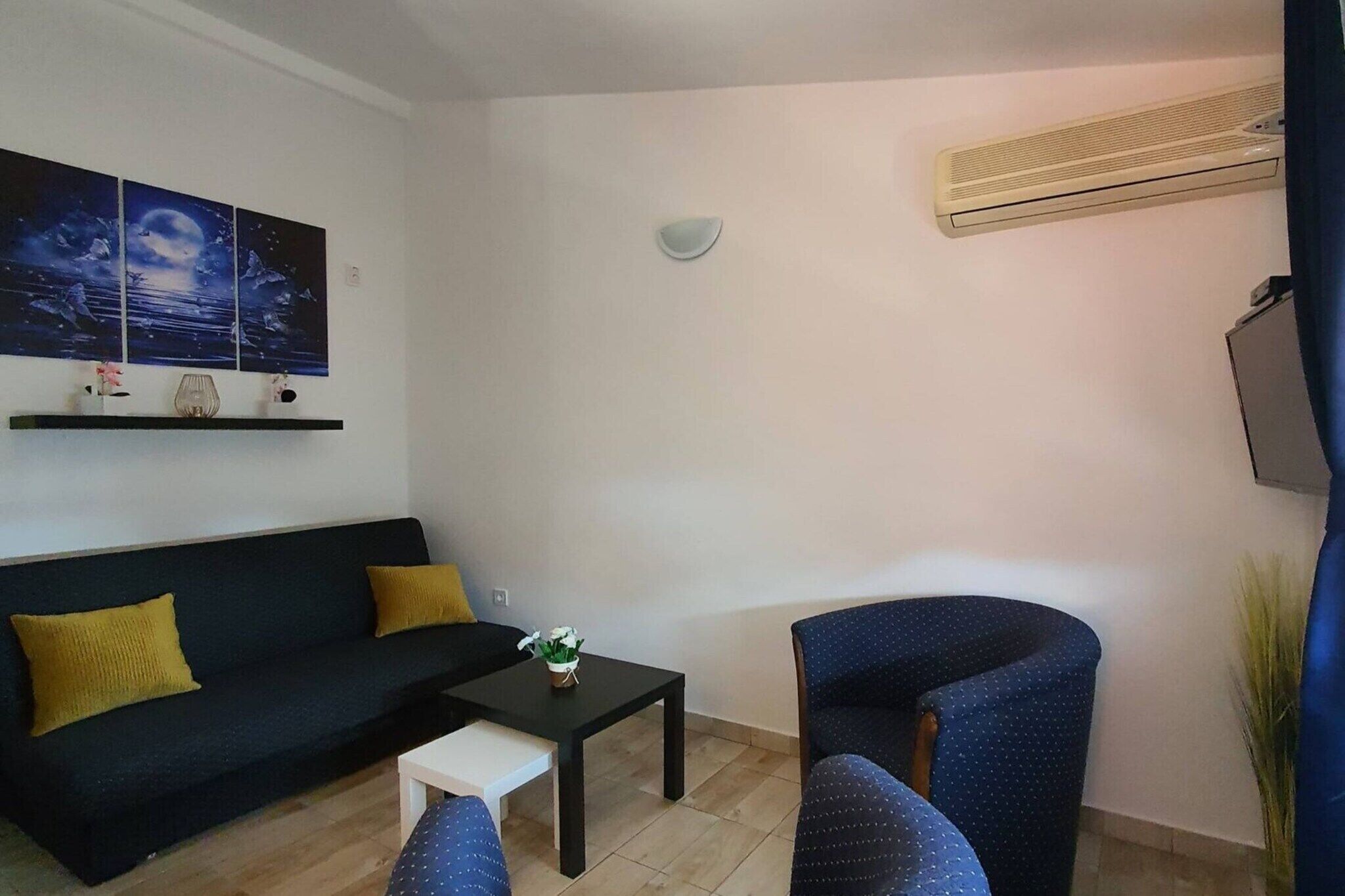 A living room with a sofa, a coffee table, a chair, and a wall-mounted air conditioner.