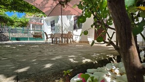 A patio area with a table and chairs, surrounded by greenery and white pebbles. - Comfort Accommodation Baošići Montenegro-One Bedroom Apartment with Terrace and Sea View (2) (Baosici)