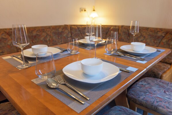 A dining table set with plates, bowls, cutlery, and wine glasses, indicating a prepared meal setting.