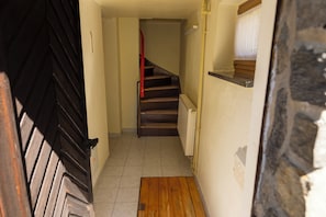 A narrow hallway with a wooden floor, a radiator on the right, and a door at the end.